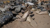 Sepatu bekas tergeletak di tengah tumpukan besar pakaian bekas di atas pasir dekat lingkungan La Mula di Alto Hospicio, Chile.