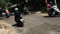 Pengendara sepeda motor melintas di Jalan Durian Raya, Jagakarsa, Jakarta Selatan, Selasa (14/12/2021). Pada pukul 10.00 WIB, beberapa titik terpantau ada sumur resapan yang belum diaspal dan dilubangi.