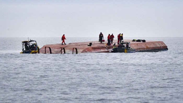 Divers work on the capsized Danish cargo ship Karin Hoej, right, after it collided with British cargo vessel Scot Carrier in the Baltic Sea, between Ystad and Bornholm, Sweden, Monday, Dec. 13, 2021. Two cargo ships collided in the Baltic Sea off southern Sweden and at least two people were reported missing Monday. One of the vessels capsized and will be towed to a Swedish port, authorities said. The maritime administration said it received a pre-dawn alarm that two cargo ships had collided south of Ystad in Sweden, close to the Danish island of Bornholm. The authority identified the ships as the Danish-flagged Karin Hoej and a British ship, the Scot Carrier. The Danish ship capsized fully and was floating upside down. (Johan Nilsson/TT via AP)