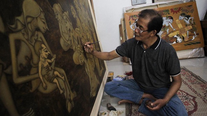 Seniman Jogja Buat Lukisan Rohani Bercorak Wayang Petrus Herjaka (64) sedang menyelesaikan lukisan bertemakan kelahiran Tuhan Yesus di studio lukis di Bantul, Yogyakarta, Selasa (14/12/2021). Lukisan dengan pendekatan teknik penggambaran wayang purwo tersebut narasi dari menyambut Natal saat pandemi.