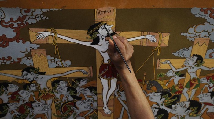Seniman Jogja Buat Lukisan Rohani Bercorak Wayang Petrus Herjaka (64) sedang menyelesaikan lukisan bertemakan kelahiran Tuhan Yesus di studio lukis di Bantul, Yogyakarta, Selasa (14/12/2021). Lukisan dengan pendekatan teknik penggambaran wayang purwo tersebut narasi dari menyambut Natal saat pandemi.