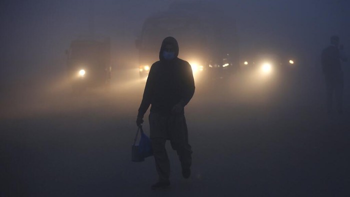 Vehicles drive as heavy fog reduces visibility, in Lahore, Pakistan, Thursday, Dec. 16, 2021. (AP Photo/K.M. Chaudary)