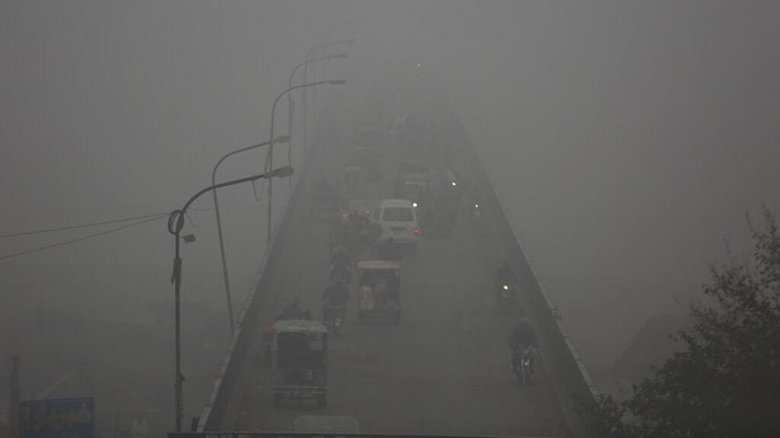 Vehicles drive as heavy fog reduces visibility, in Lahore, Pakistan, Thursday, Dec. 16, 2021. (AP Photo/K.M. Chaudary)