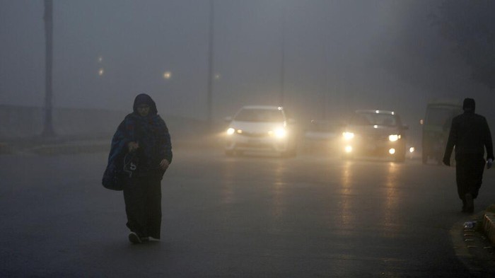 Vehicles drive as heavy fog reduces visibility, in Lahore, Pakistan, Thursday, Dec. 16, 2021. (AP Photo/K.M. Chaudary)