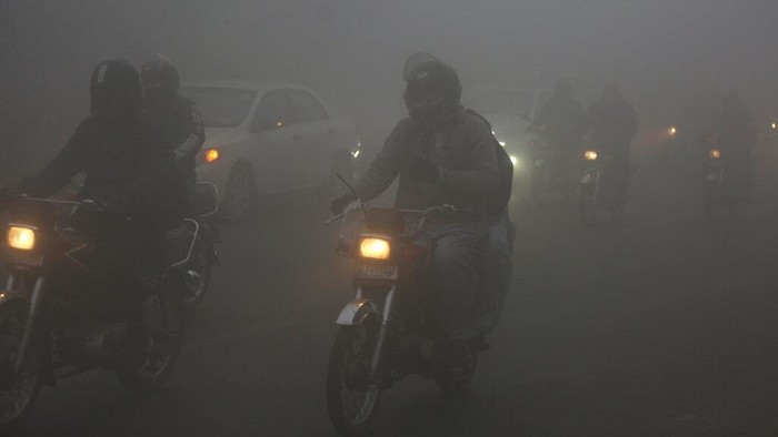 Vehicles drive as heavy fog reduces visibility, in Lahore, Pakistan, Thursday, Dec. 16, 2021. (AP Photo/K.M. Chaudary)