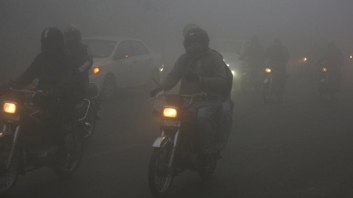 Kabut Tebal Selimuti Kota Paling Tercemar Ketiga di Dunia Vehicles drive as heavy fog reduces visibility, in Lahore, Pakistan, Thursday, Dec. 16, 2021. (AP Photo/K.M. Chaudary)