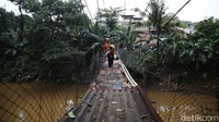 Warga melintasi jembatan gantung Srengseng Sawah yang mulai rusak, Kamis (16/12/2021).