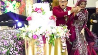 Tapi, saat memotong bagian atas kue, tubuh Danang DA dan Hemas Nura terlihat menyenggol meja dan menyebabkan bagian atas kue pernikahan mereka terjatuh. Foto: dok. Channel Youtube Danang Official