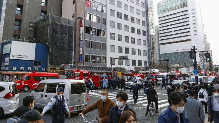 Rescuers gather in front of a building where a fire broke out in Osaka, western Japan Friday, Dec. 17, 2021.  Japan's NHK says a fire broke out in the building and dozens of people were feared dead. (Yukie Nishizawa/Kyodo News via AP)