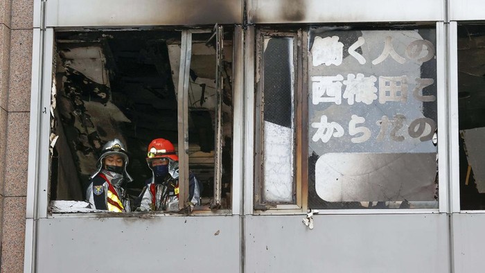 Rescuers gather in front of a building where a fire broke out in Osaka, western Japan Friday, Dec. 17, 2021.  Japan's NHK says a fire broke out in the building and dozens of people were feared dead. (Yukie Nishizawa/Kyodo News via AP)