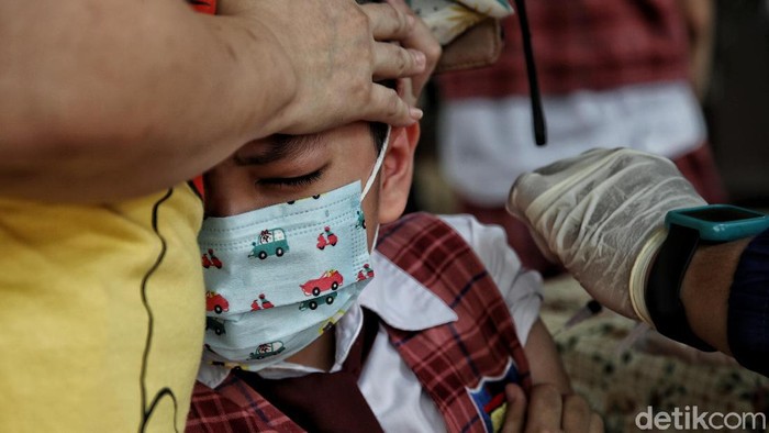 Vaksinator memberi vaksin Sinovac dosis pertama  kepada anak-anak di kawasan Perumahan Layar Permai, Pantai Indah Kapuk, Jakarta Utara, Jumat (17/12).