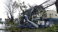 Seorang polisi berjalan melewati bangunan yang rusak akibat Topan Rai di kota Cebu, Filipina tengah pada Jumat, 17 Desember 2021. Topan kuat menghantam Filipina tenggara pada Kamis, menumbangkan pohon, merobek atap seng dan merobohkan listrik saat bertiup di seluruh provinsi pulau di mana hampir 100.000 orang telah dievakuasi. AP/Jay Labra