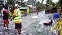 Warga Pagnamitan, Guiuan, Samar Timur, Filipina timur mengarungi jalan yang terendam banjir akibat Topan Rai. (AP Photo/Alren Beronio)