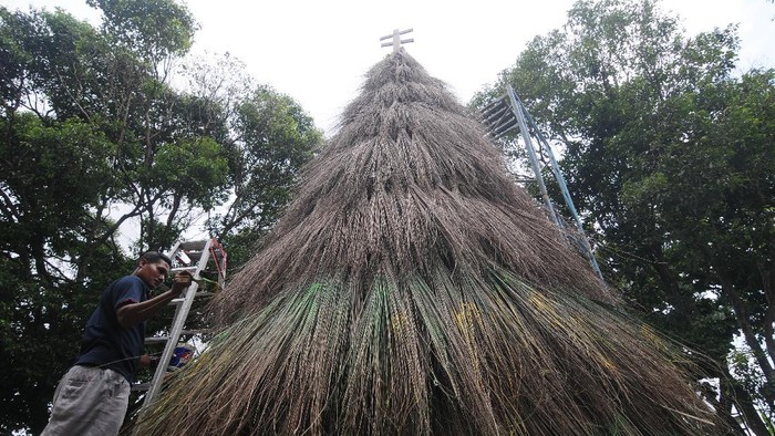 Petugas gereja memasang kayu salib saat membuat pohon Natal dari sapu lidi di Gereja Katolik Santa Perawan Maria Bunda Kristus, Wedi, Klaten, Jawa Tengah, Sabtu (18/12/2021). Pohon Natal yang terbuat dari susunan sapu lidi itu sebagai lambang kekompakan dan persatuan gerak langkah umat Katolik, sehingga menjadi kuat, rukun, tangguh dan berbuah antarsesama manusia dalam menyambut hari besar kelahiran Yesus Kristus. ANTARA FOTO/Aloysius Jarot Nugroho/nym.