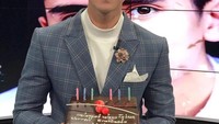 Pernah menjadi presenter dalam program infotainment, Verrell sangat tampan dengan balutan jas berwarna abu-abu. Ia juga terlihat merayakan ulang tahun bersama seloyang cake. Foto: Instagram @bramastavrl