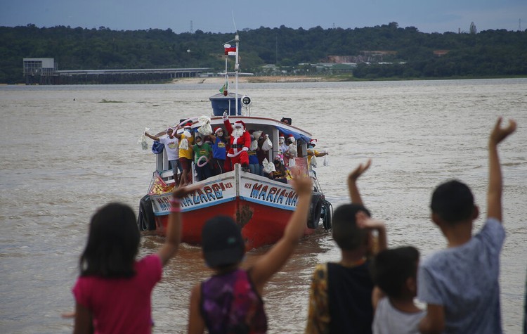 Arungi Sungai Amazon, Sinterklas Bagikan Hadiah untuk Anak-anak Seorang pria mengenakan kostum Sinterklas saat mengarungi sungai Amazon untuk bagikan hadiah kepada anak-anak di lembah Amazon. Ini potretnya.