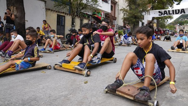 Sejumlah anak berkumpul di kawasan Caracas, Venezuela, untuk mengikuti balapan dengan menaiki papan kayu pada beroda pada Sabtu (18/12/2021) waktu setempat.