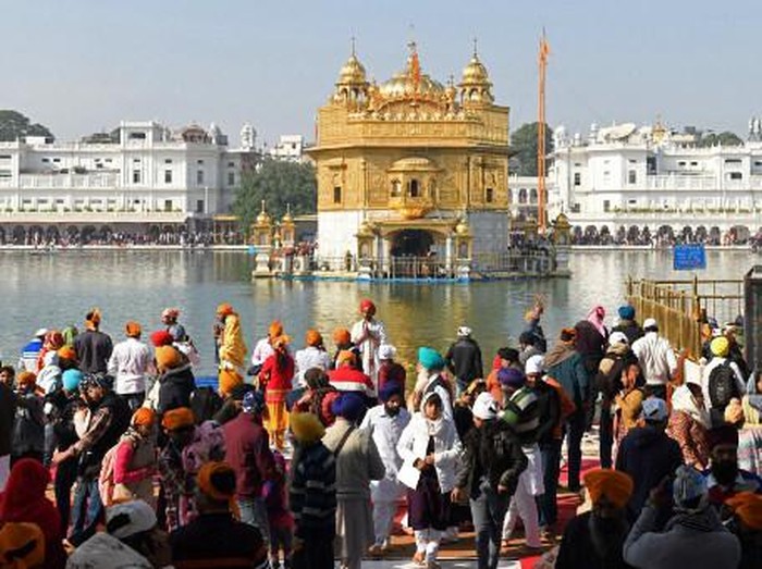 Sikh devotees walk inside the complex of Golden Temple in Amritsar on December 19, 2021, a day after a man was beaten to death for allegedly trying to commit an act of sacrilege at the holiest shrine of the Sikh faith. (Photo by Narinder NANU / AFP)