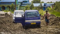 Warga melihat mobilnya yang terjebak di jalan Trans Kalimantan yang rusak di Kecamatan Liang Anggang, Banjarbaru, Kalimantan Selatan, Minggu (19/12/2021).