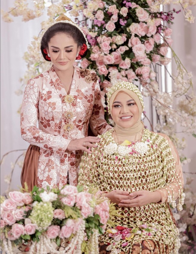 Krisdayanti mengenakan kebaya model Kartini warna soft pink dengan motif bunga. Aksen mawar di bagian pundak dan selendang yang menyampir ke bawah membuat kebaya berpotongan simpel ini memiliki sedikit twist. Foto: Instagram