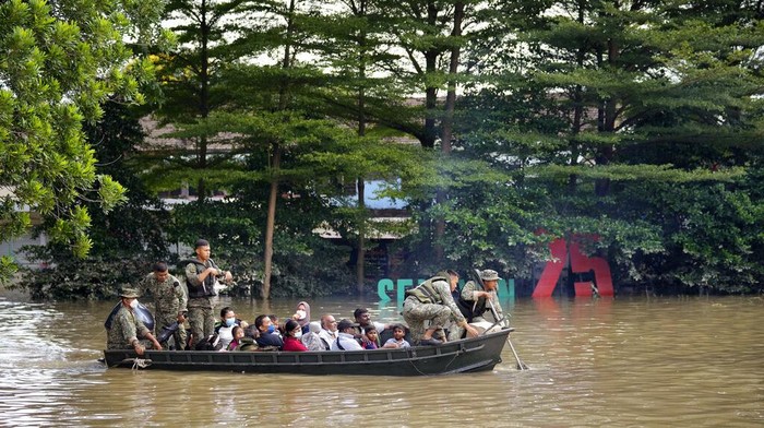 Warga mengarungi jalan yang banjir di Shah Alam, di pinggiran Kuala Lumpur, Malaysia, Senin, 20 Desember 2021. Layanan penyelamatan pada Senin bekerja untuk membebaskan ribuan orang yang terjebak banjir terparah Malaysia dalam beberapa tahun setelah hujan lebat berhenti menyusul lebih banyak lagi. dari tiga hari hujan deras di ibu kota dan di seluruh negeri. (Foto AP/Vincent Thian)