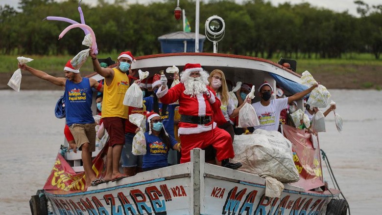 A member of the Amigos do Papai Noel group, wearing a Santa Claus costume, arrives to Careiro da Varzea, Brazil, a city on the shores of the Amazon River, to give presents to the children, on December 18, 2021. - Amigos do Papai Noel (Friends of Santa Claus) is a group of people dedicated to promoting Christmas for underprivileged children in the city of Manaus, rural and riverside communities in the Amazon. (Photo by MICHAEL DANTAS / AFP)