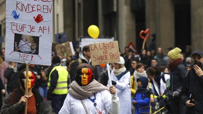 Demo COVID Belgia Para pengunjuk rasa berbaris selama demonstrasi menentang tindakan COVID-19 di Brussel, Minggu, 19 Desember 2021. Ribuan pengunjuk rasa berdemonstrasi melalui pusat Brussel pada hari Minggu untuk ketiga kalinya menentang pembatasan COVID-19 yang diberlakukan oleh pemerintah Belgia untuk melawan lonjakan infeksi dan munculnya varian omicron yang mengkhawatirkan. Tanda di sebelah kiri bertuliskan 'Jauhi anak-anak kita', dan tanda di sebelah kanan bertuliskan 'Bebas dari suntikan'. (Foto AP/Olivier Matthys)