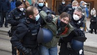 Petugas polisi menahan seorang peserta demonstrasi menentang tindakan COVID-19 di Frankfurt, Jerman, Sabtu, (18/12/2021). AP/Boris Roessler