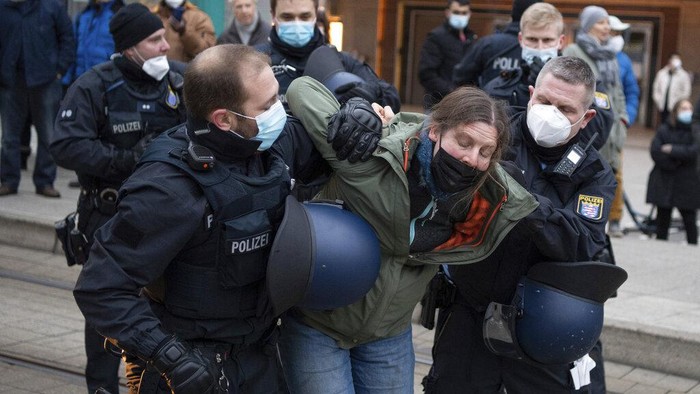 Demo COVID Jerman Petugas polisi menahan seorang peserta demonstrasi menentang tindakan COVID-19 di Frankfurt, Jerman, Sabtu 18 Desember 2021. (Boris Roessler/dpa via AP)