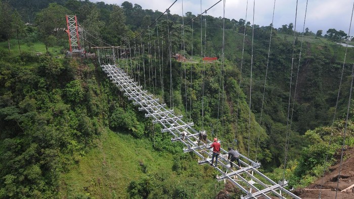 Dusun Terpencil di Lereng Merapi Bakal Punya Jembatan Gantung Sejumlah pekerja membawa kerangka besi saat membangun jembatan gantung di lereng Gunung Merapi, Tegalmulyo, Kemalang, Klaten, Jawa Tengah, Sabtu (18/12/2021). Pembangunan jembatan gantung tersebut diharapkan dapat mempermudah akses bagi warga yang tinggal di kampung terpencil Girpasang serta mendukung pengembangan pariwisata di kawasan tersebut. ANTARA FOTO/Aloysius Jarot Nugroho/foc.
