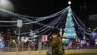 Seorang wanita Aymara berbicara di telepon selulernya di alun-alun Tejada Sorzano yang dihiasi dengan lampu liburan, di La Paz, Bolivia, Senin, (13/12/2021). (AP Photo/Juan Karita)