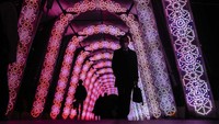 Orang-orang berjalan melalui terowongan pajangan lampu liburan Kamis, (9/12/2021), di Tokyo. (Foto AP/Kiichiro Sato)