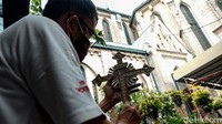 Sebuah salib bertuliskan INRI (Iesus Nazarenus, Rex Iudaeorum) tengah dibersihkan pekerja.