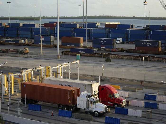 Trucks hauling containers depart from PortMiami, Thursday, Dec. 16, 2021, in Miami. Inflation has been a growing concern throughout 2021. Higher raw materials costs and supply chain problems have been raising overall costs for businesses, which have raised prices on goods to offset the impact. (AP Photo/Rebecca Blackwell)