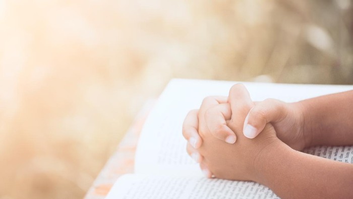 Little child girl hands folded in prayer on a Holy Bible for faith,spirituality and religion concept in vintage color tone