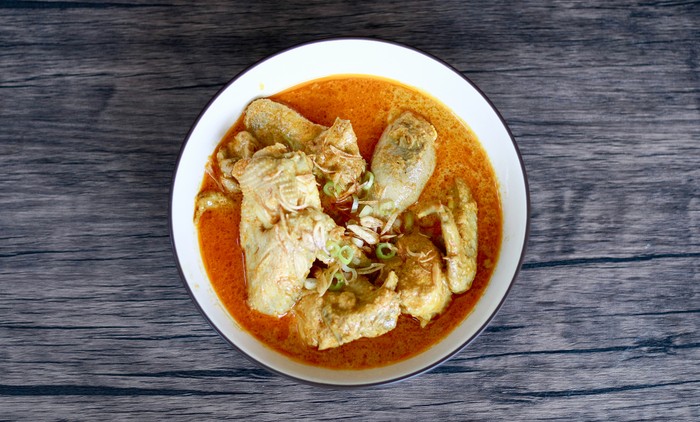 Indonesian gulai ayam or Indonesian chicken curry in a bowl on wood background.