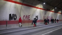 Para migran menuju Prancis dari Italia berjalan melewati grafiti bertuliskan No One is Illegal di terowongan menuju perbatasan Prancis-Italia.