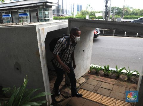 Pejalan kaki melintas di antara material beton saluaran air/gorong-gorong yang berada di jalur pedestrian, kawasan Gatot Subroto, Jakarta, Selasa (21/12). (CNBC Indonesia/Muhammad Sabki)