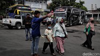 Petugas membantu calon penumpang menuju bus yang ditumpangi.