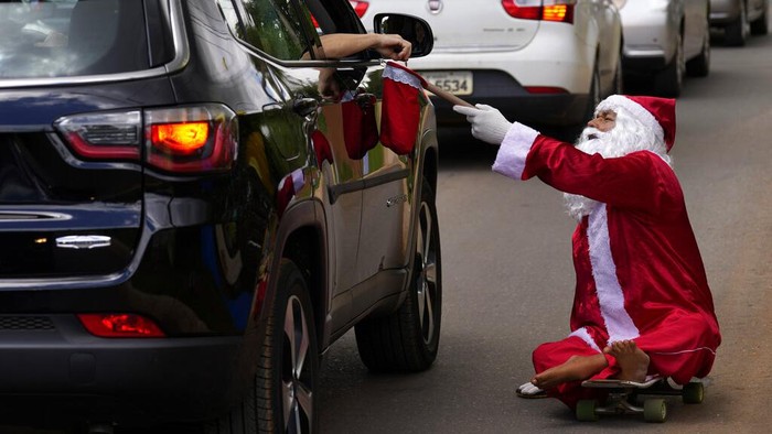 Jose Ivanildo, who lost the use of his legs due to infantile paralysis, uses a skate board as he begs for money at a traffic light dressed as Santa Claus in Brasilia, Brazil, Tuesday, Dec. 21, 2021. The 48-year-old, known as 