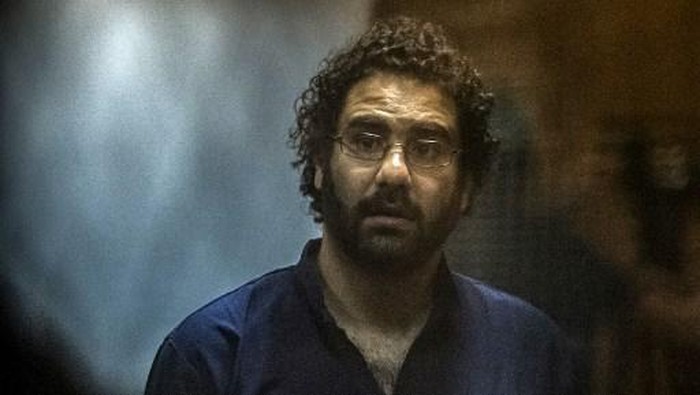 Egyptian activist and blogger Alaa Abdel Fattah gestures from behind the defendants cage during his trial for insulting the judiciary alongside 25 other defendants including ousted Egyptian president Mohamed Morsi, who was recently sentenced to death, in Cairo on May 23, 2015. AFP PHOTO / KHALED DESOUKI (Photo by KHALED DESOUKI / AFP)