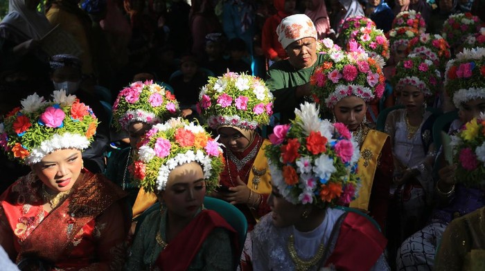 Sejumlah gadis mengikuti upacara adat Ngarot di Desa Lelea, Indramayu, Jawa Barat, Rabu (22/12/2021). Acara yang diikuti puluhan pemuda dan pemudi berhiaskan mahkota bunga itu merupakan pesta menjelang musim tanam padi sebagai wujud suka cita masyarakat atas berkah yang diberikan sang pencipta. ANTARA FOTO/Dedhez Anggara/aww.