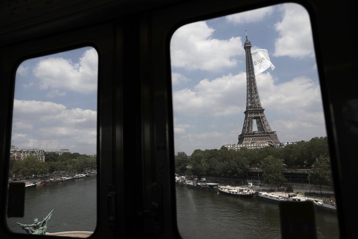 Gambar dari kereta bawah tanah yang ditinggikan, sebuah bendera raksasa berkibar di Menara Eiffel di Paris, Selasa, 8 Juni 2021. Alasan peristiwa itu tidak segera diketahui. (Foto AP/Lewis Joly)