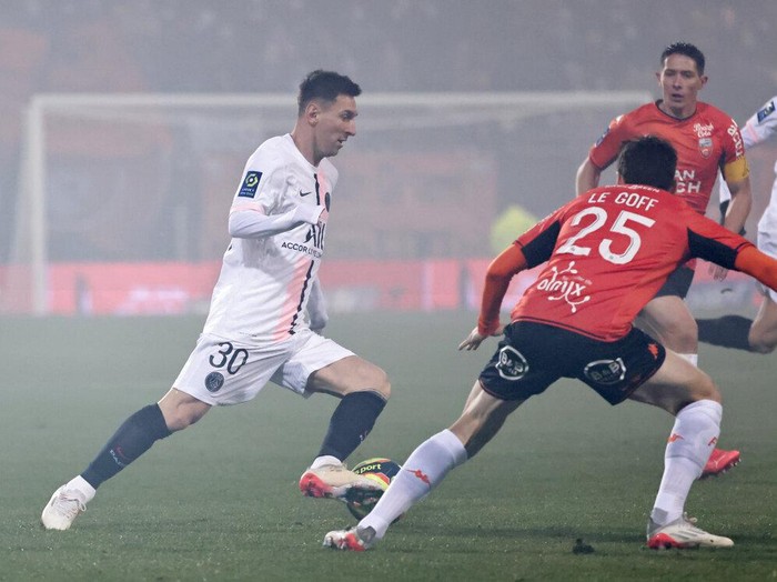 PSG's Lionel Messi, left, and Lorient's Vincent Le Goff challenge for the ball during the French League One soccer match between FC Lorient and Paris Saint-Germain at the Moustoir stadium in Lorient, western France, Wednesday, Dec. 22, 2021. (AP Photo/Jeremias Gonzalez)
