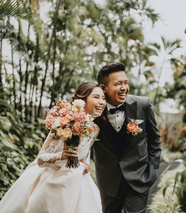 Sementara Joshua Suherman memakai setelan jas yang didominasi abu-abu, kemeja putih, dan dasi kupu-kupu berwarna hitam. Tersemat bunga oranye pada saku setelan rancangan SAS Designs tersebut. Foto: dok. Instagram thebridestory