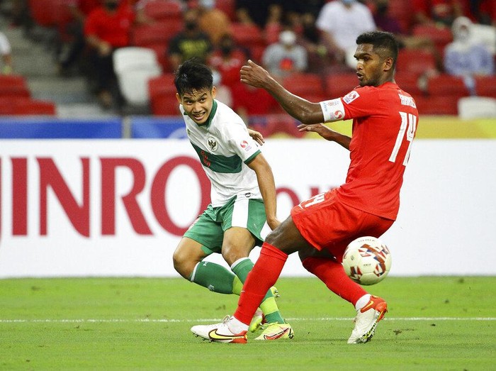 Witan Sulaeman of Indonesia, left, shoots past Hariss Harun of Singapore during the AFF Suzuki Cup 2020 semi-final first leg soccer match between Singapore and Indonesia in Singapore, Wednesday, Dec. 22, 2021. (AP Photo/Suhaimi Abdullah)