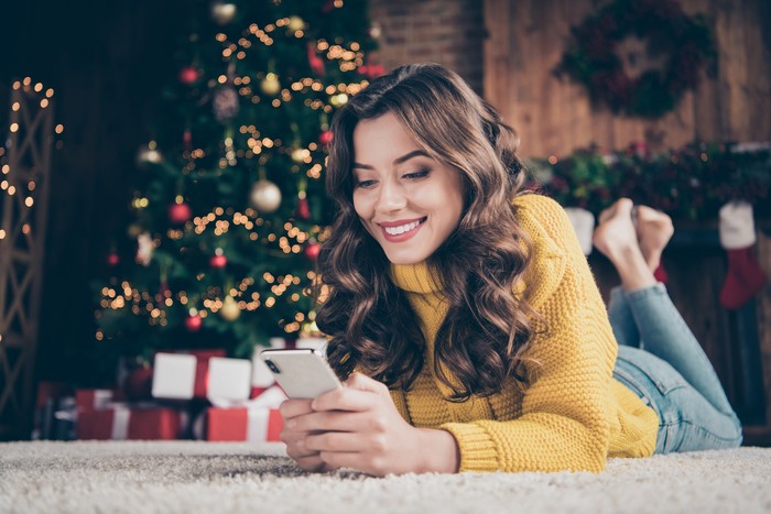 Low below angle view photo of charming, cute beautiful attractive girlfriend browsing through her phone in search of something while wearing jeans denim yellow sweater