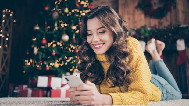 Low below angle view photo of charming, cute beautiful attractive girlfriend browsing through her phone in search of something while wearing jeans denim yellow sweater