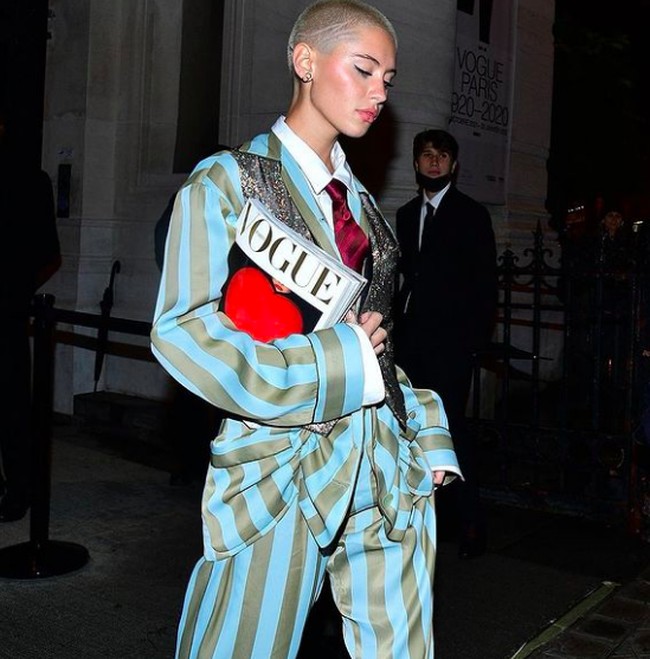 Iris Law tampil boyish dengan setelan blazer dan celana garis-garis lengkap dengan dasi. Ia tampil sambil membawa majalah Vogue. IniFoto: dok. Instagram/@lirisaw
