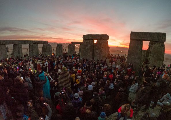 WILTSHIRE, ENGLAND - DECEMBER 22: Participants enjoy the sunset at Stonehenge on December 22, 2021 in Amesbury, United Kingdom. Along with the live stream, English Heritage, which manages the site, has allowed visitors into the event for the first time since the pandemic. The event is claimed to be more important in the pagan calendar than the summer solstice because it marks the 're-birth' of the Sun for the New Year. (Photo by Finnbarr Webster/Getty Images)